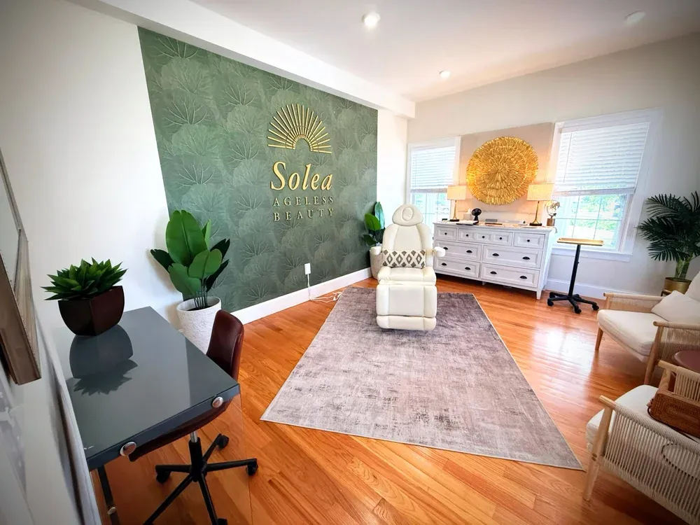 The treatment room at Solea Ageless Beauty with a sage green wall and treatment chair